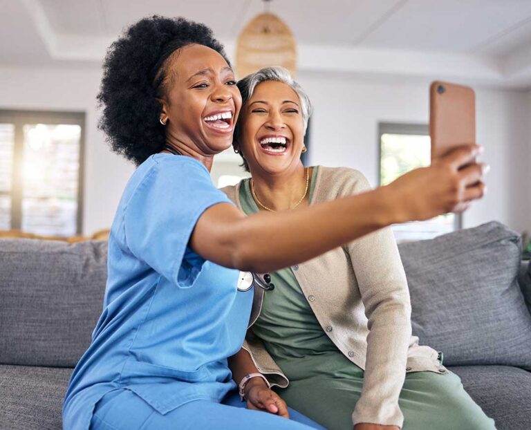 Older LGBTQ+ residents and caregivers share a respectful conversation in a bright assisted living common room.