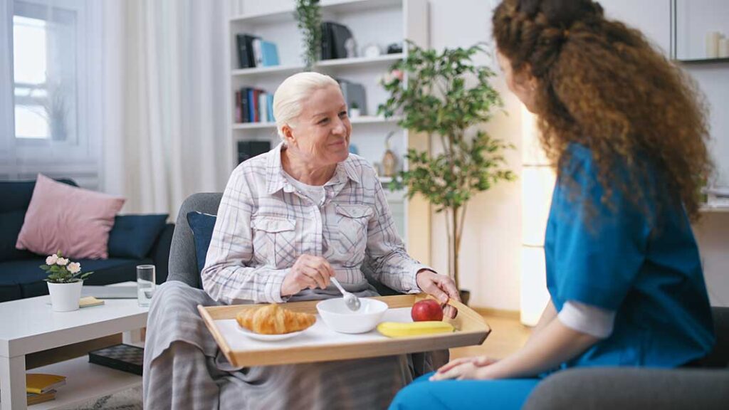 Older adult and family member reviewing a care assessment checklist at a kitchen table.