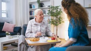 Older adult and family member reviewing a care assessment checklist at a kitchen table.