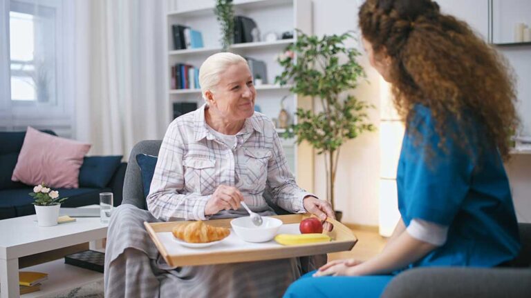 Older adult and family member reviewing a care assessment checklist at a kitchen table.